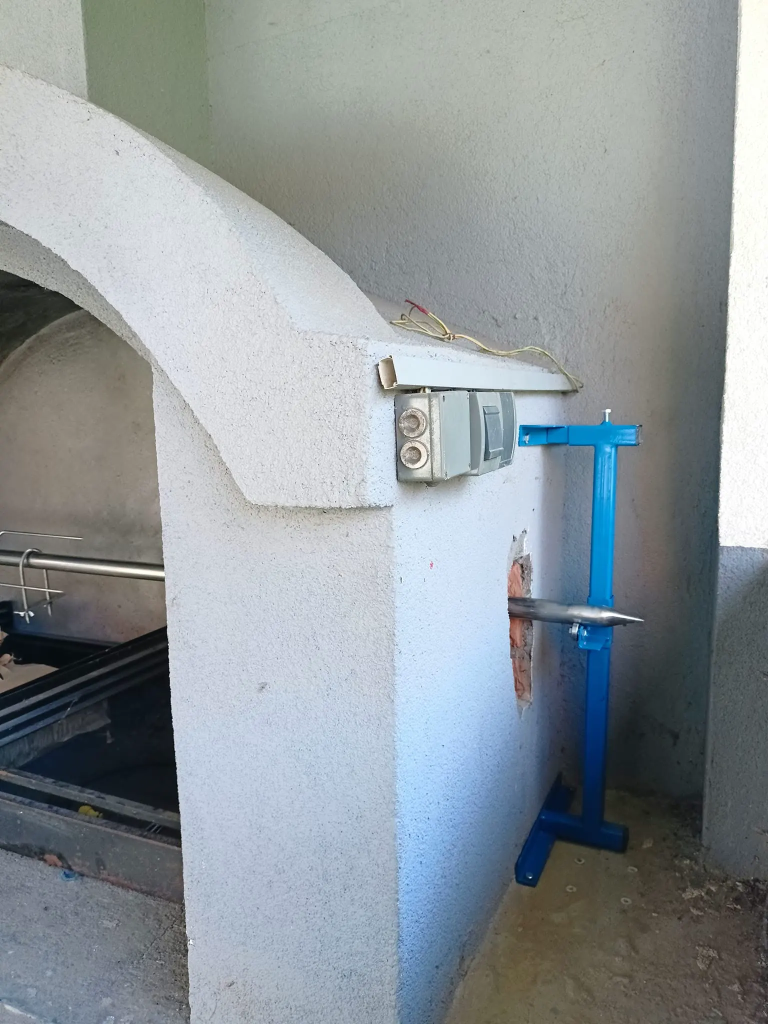 Mehanizam montiran na bočni zid pečenjare, ražanj prolazi kroz zid